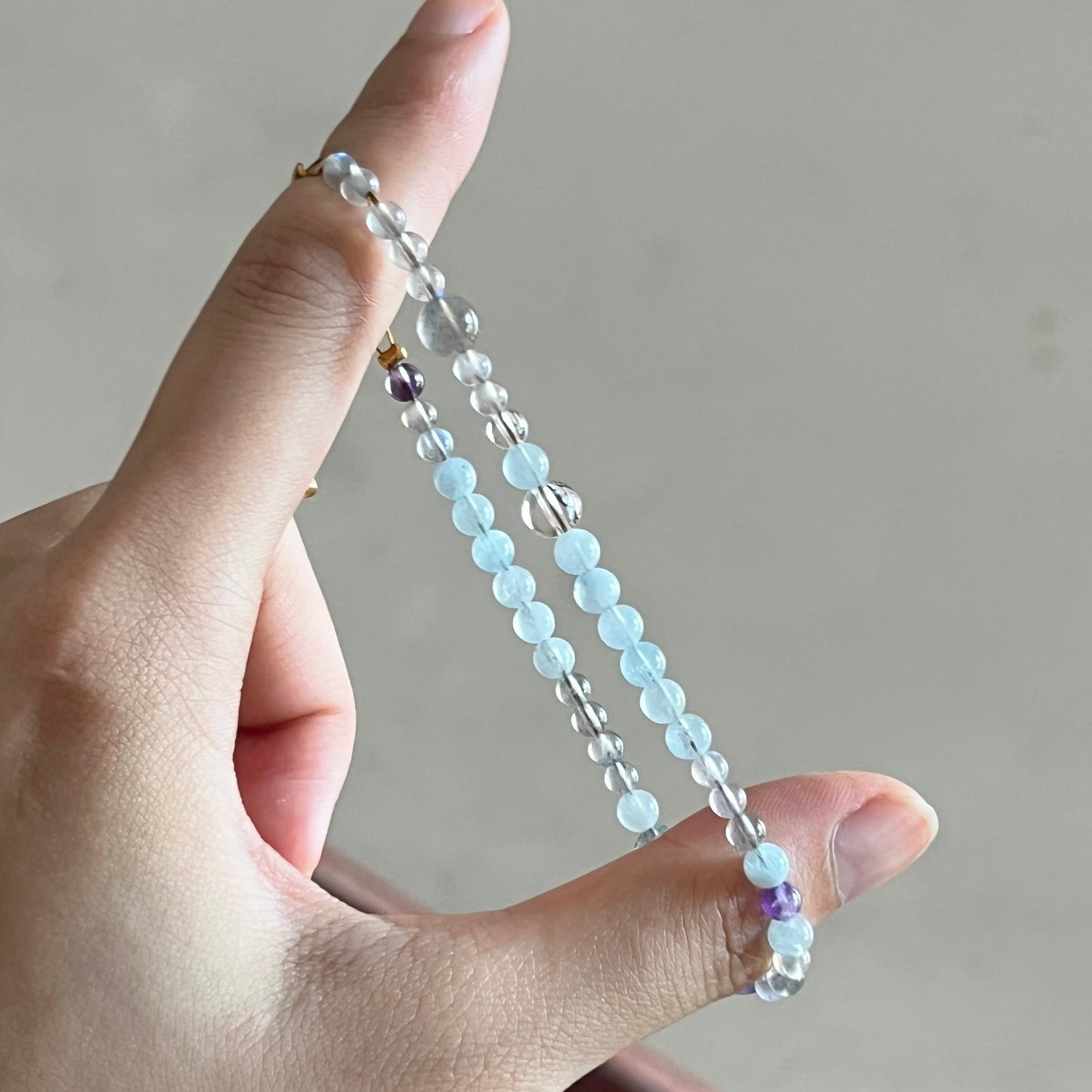 Hand holding a beaded bracelet against a neutral background