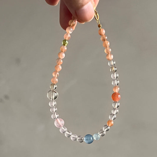 Hand holding a beaded Bracelet with multicolored beads against a neutral background