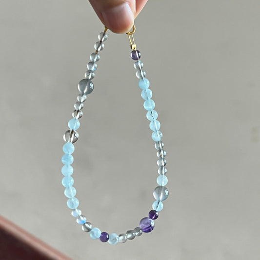 Hand holding a beaded bracelet with a neutral background