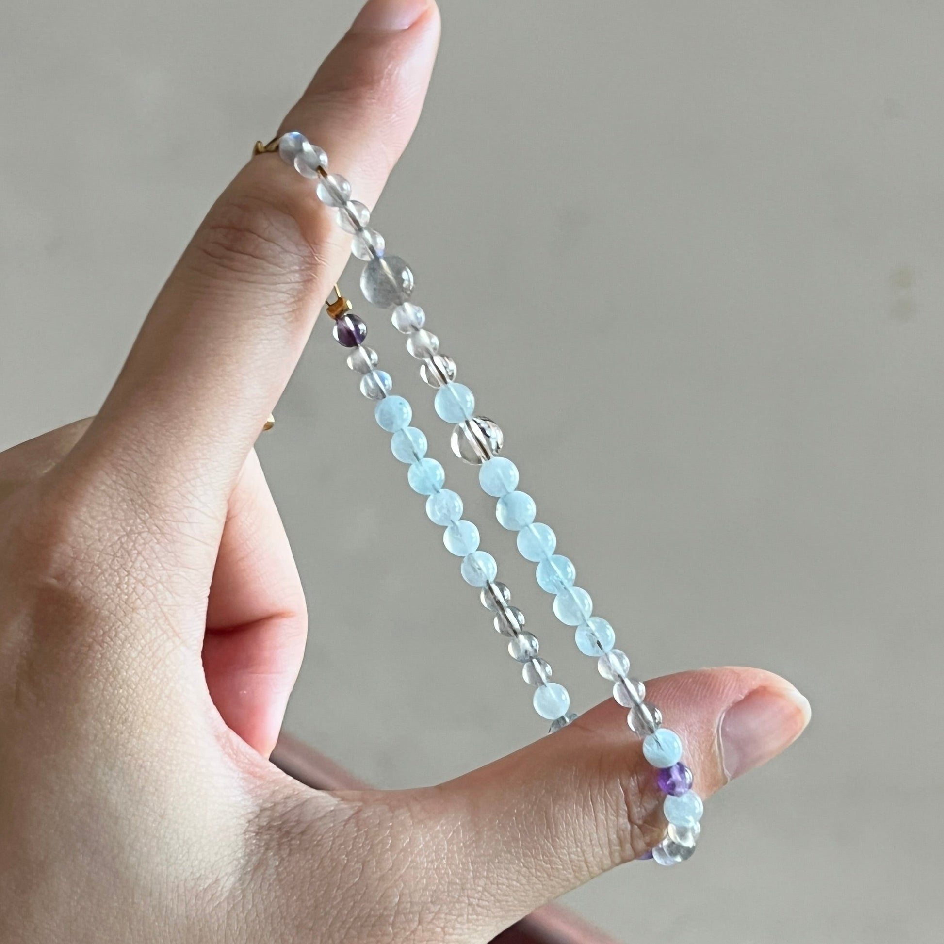 Hand holding a beaded bracelet against a neutral background