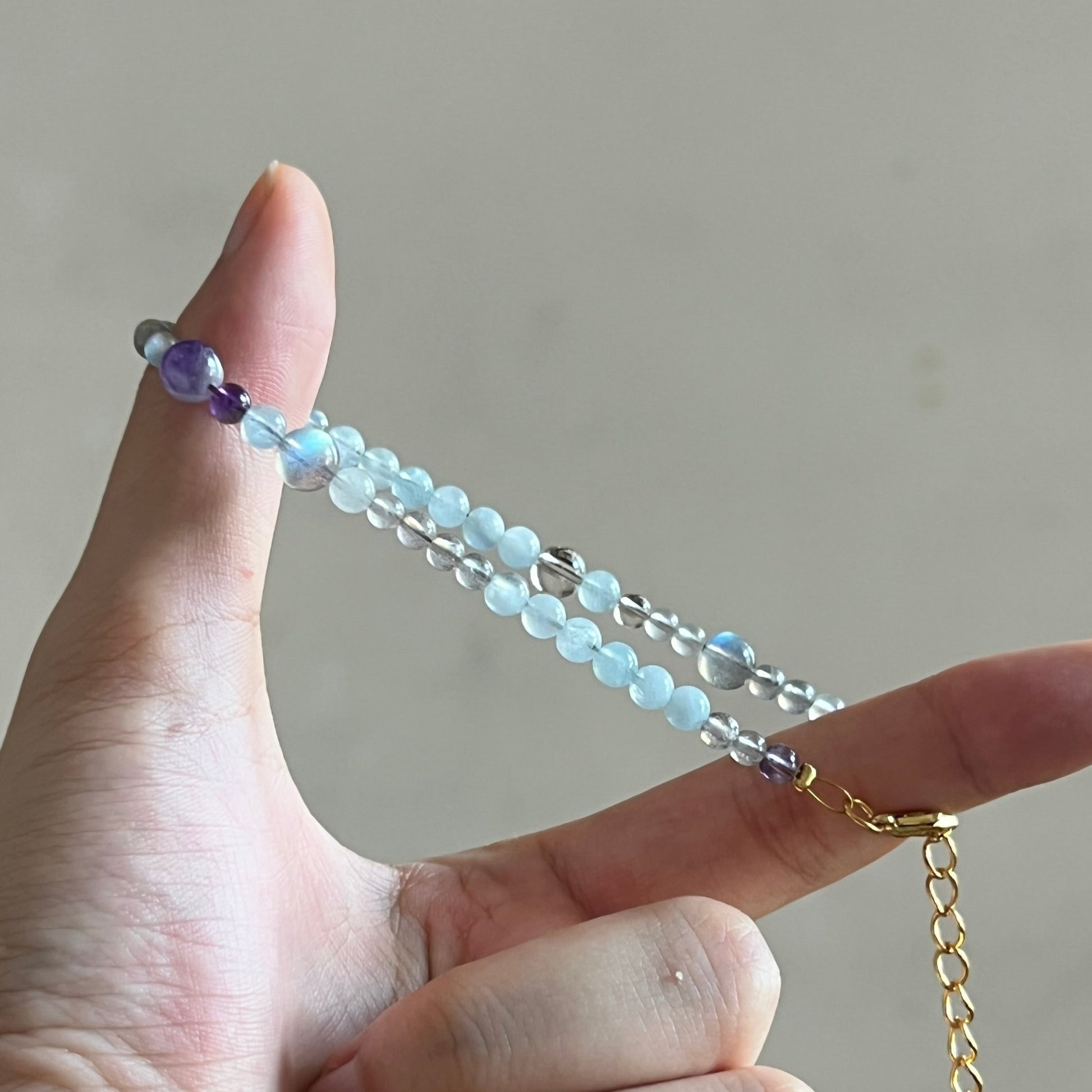 Hand holding a beaded bracelet with a plain background
