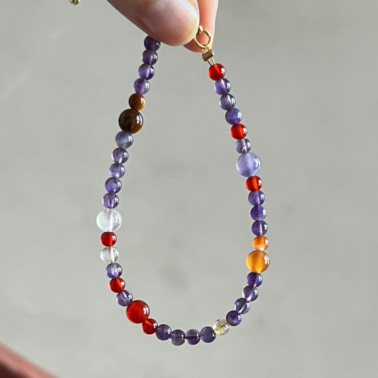 Beaded bracelet with multicolor beads held by a hand against a neutral background