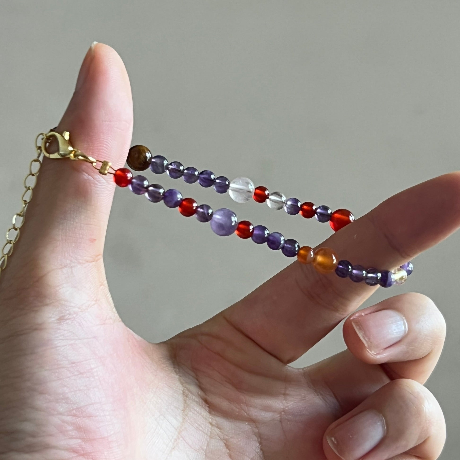 Hand holding a beaded bracelet with a neutral background