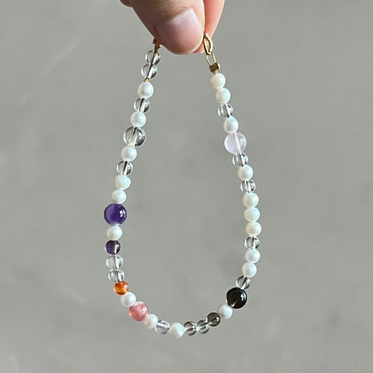 Hand holding a beaded bracelet with multicolored beads against a neutral background