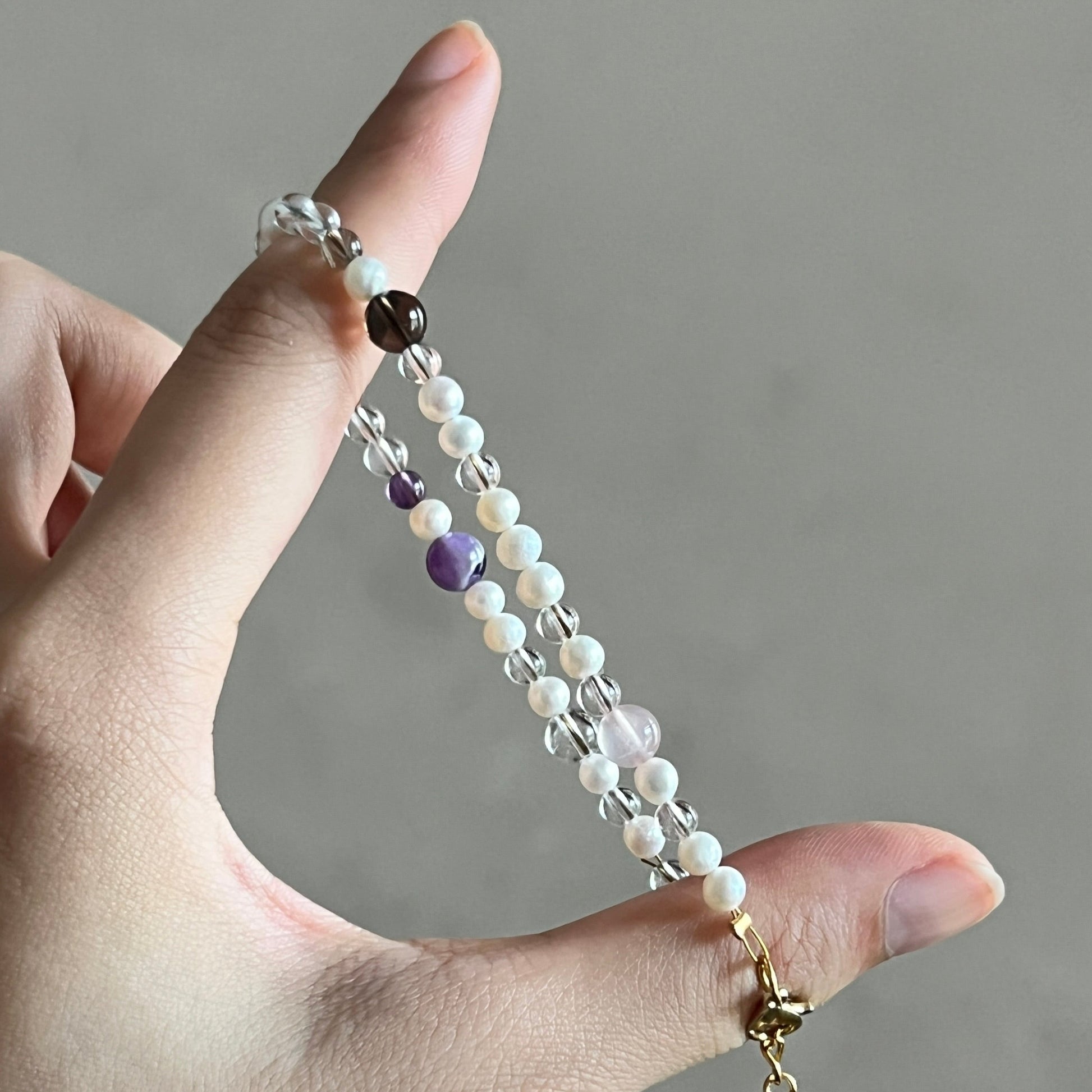 Hand holding a beaded chain against a neutral background