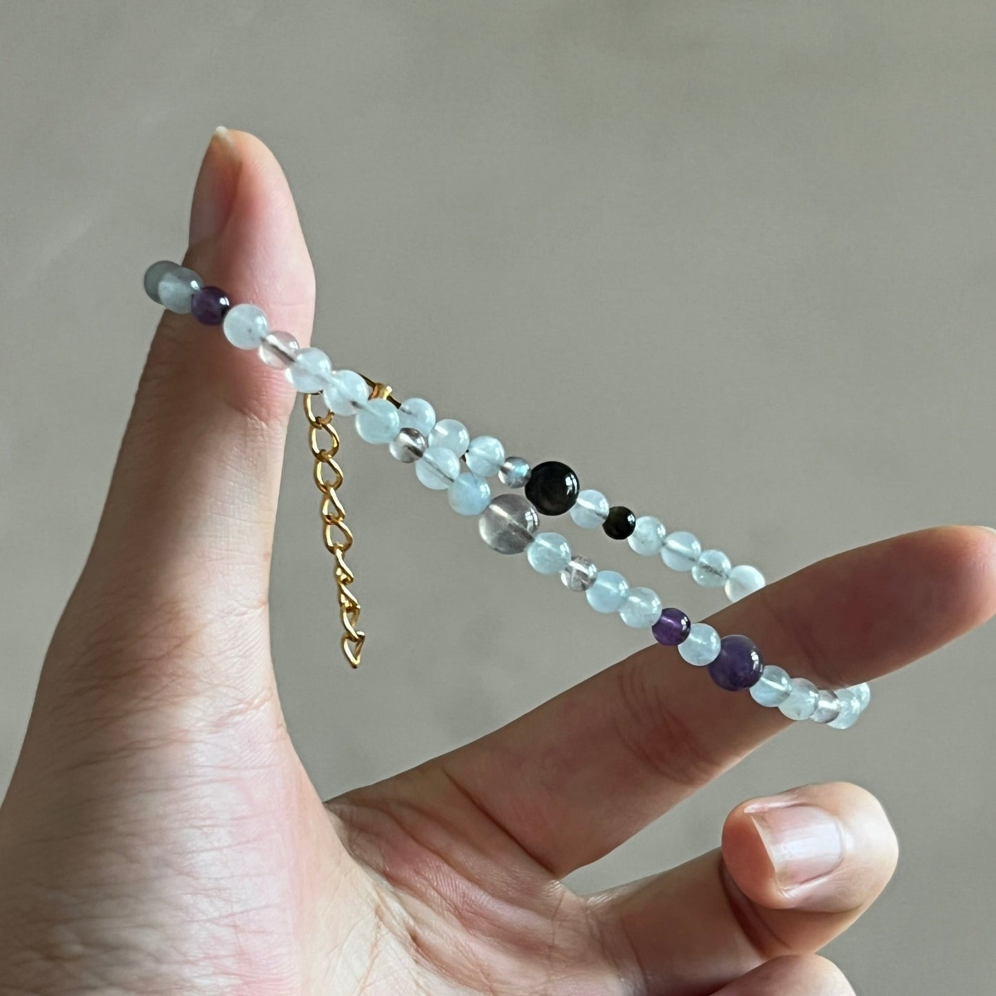 Hand holding a beaded bracelet with a neutral background