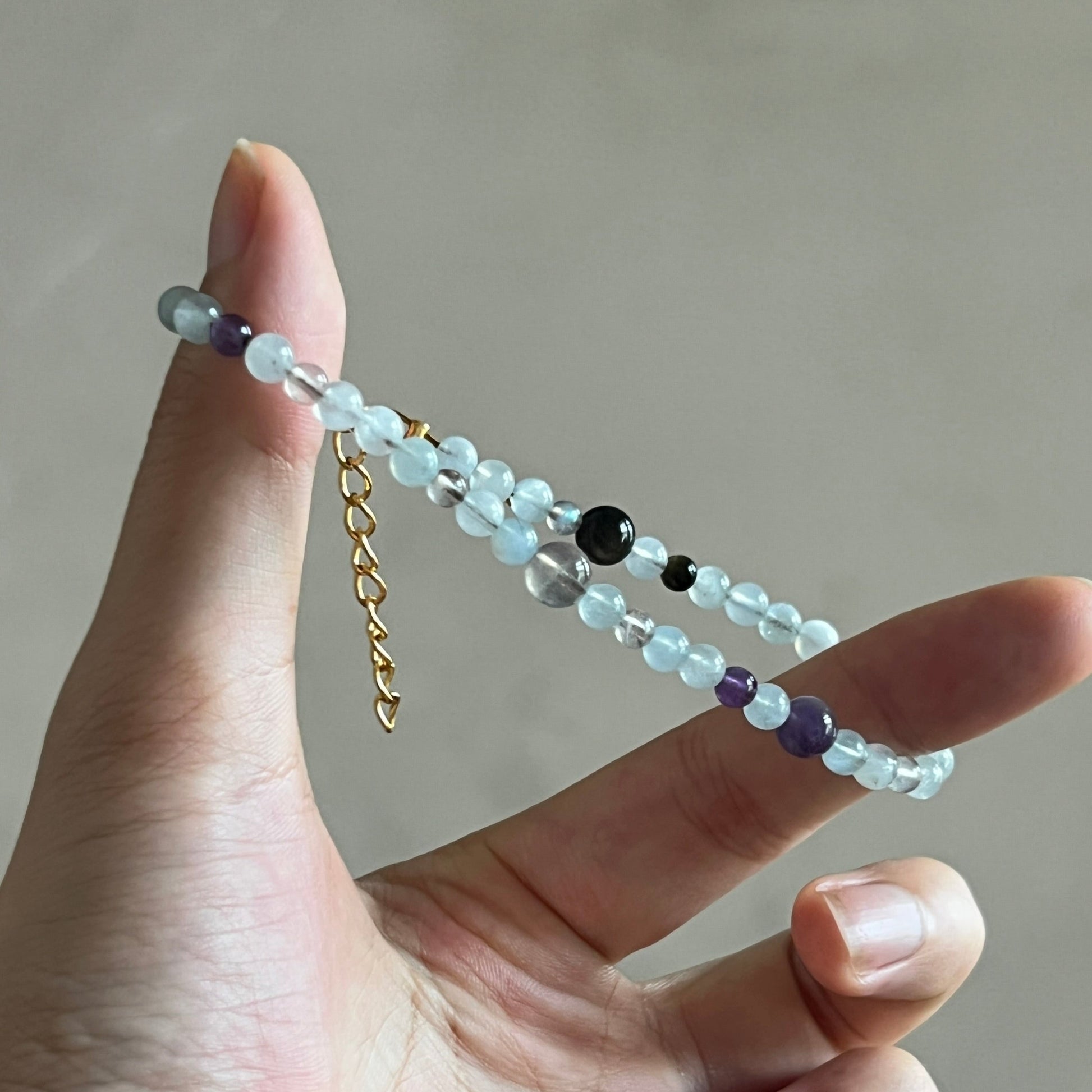 Hand holding a beaded bracelet with a neutral background