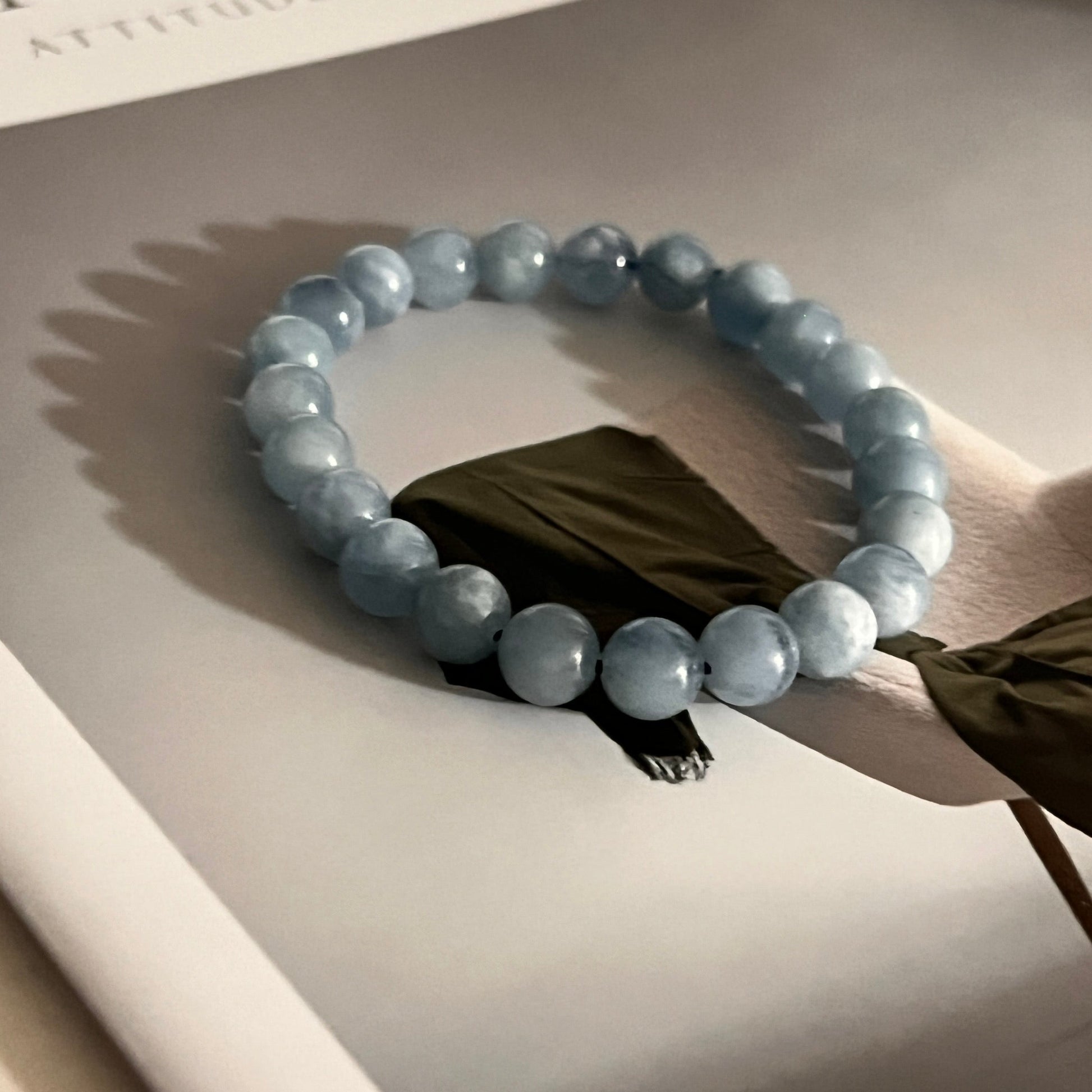 Beaded aquamarine bracelet on a light surface with a magazine in the background