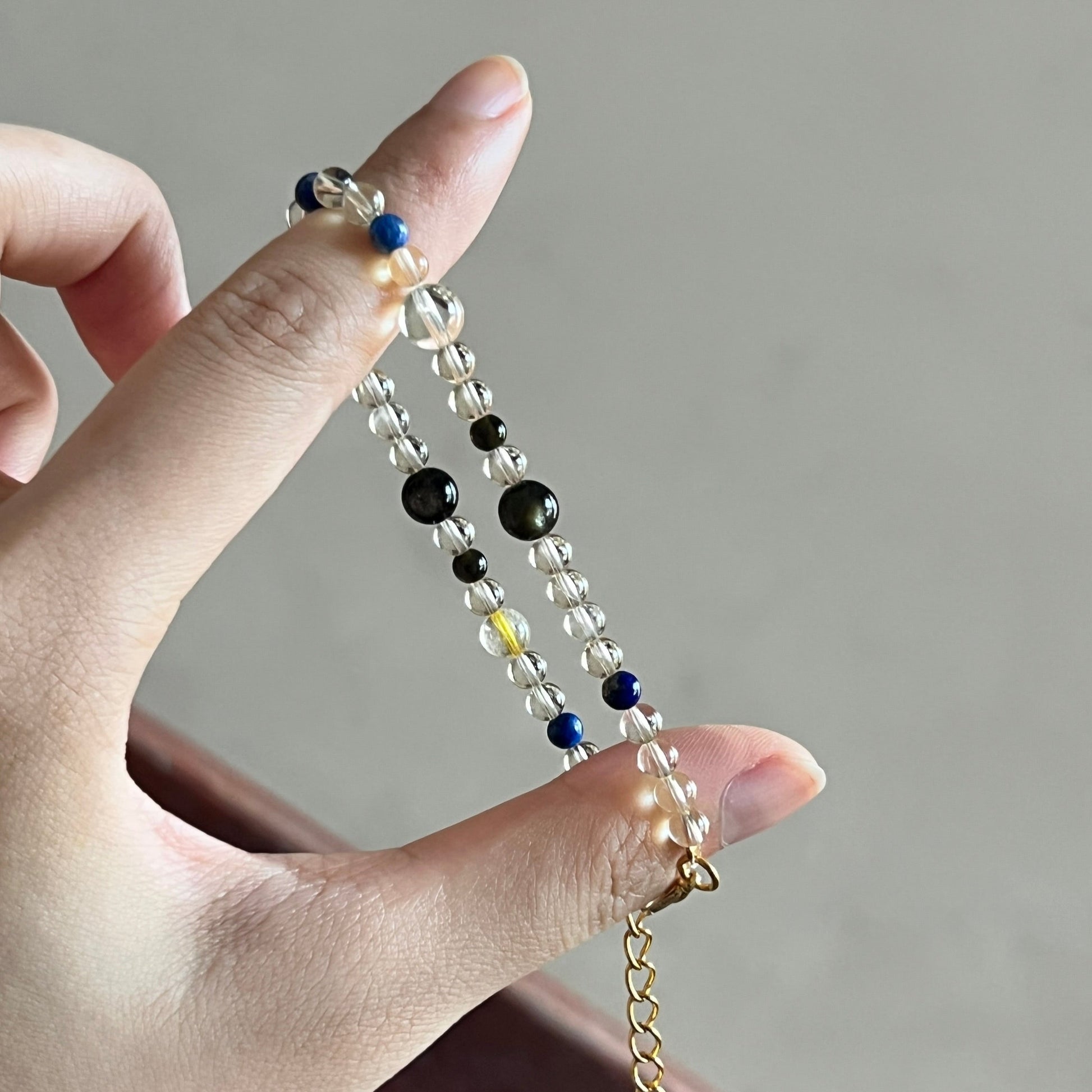Hand holding a colored crystal bracelet  against a neutral background