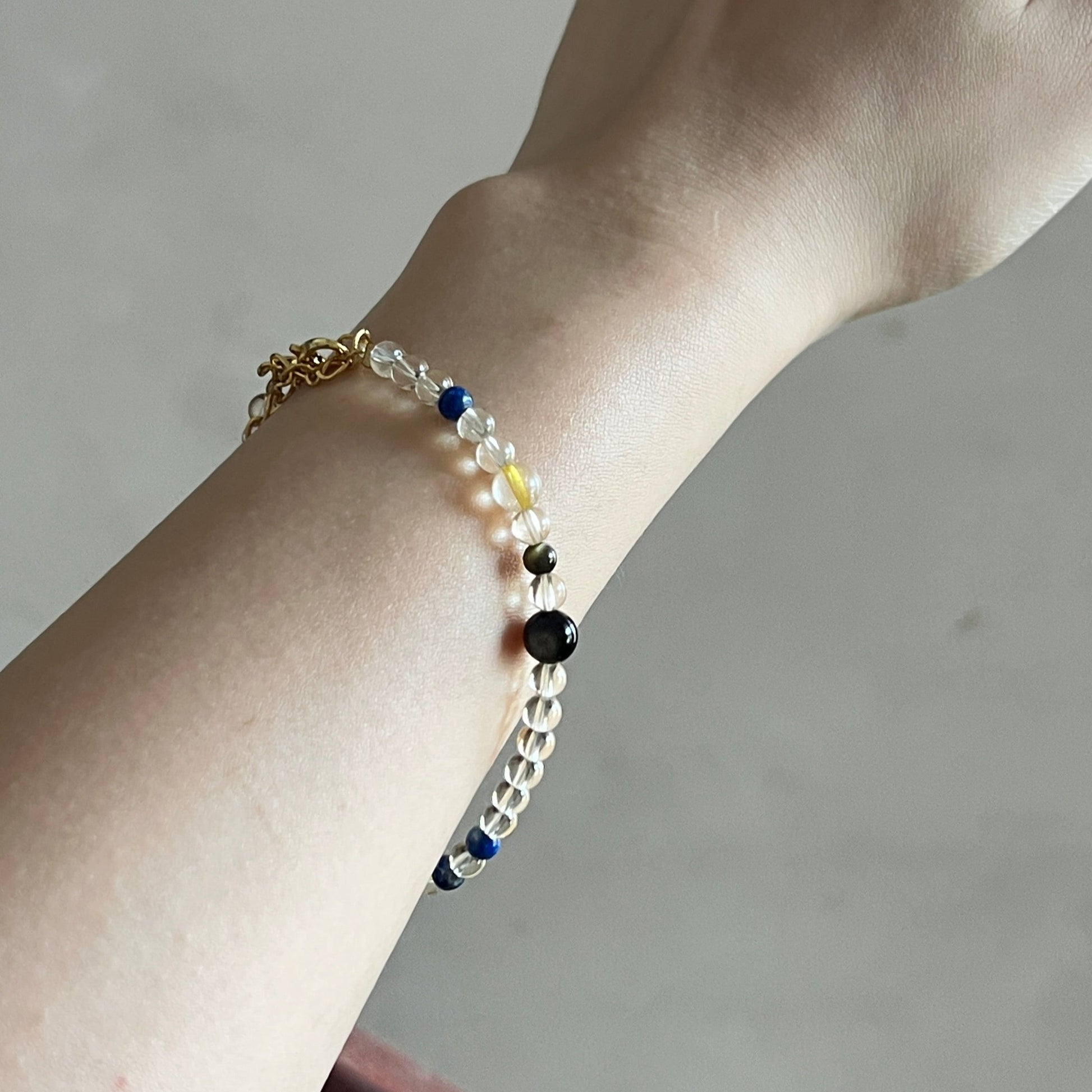 Hand wearing a bracelet with colorful beads on a neutral background