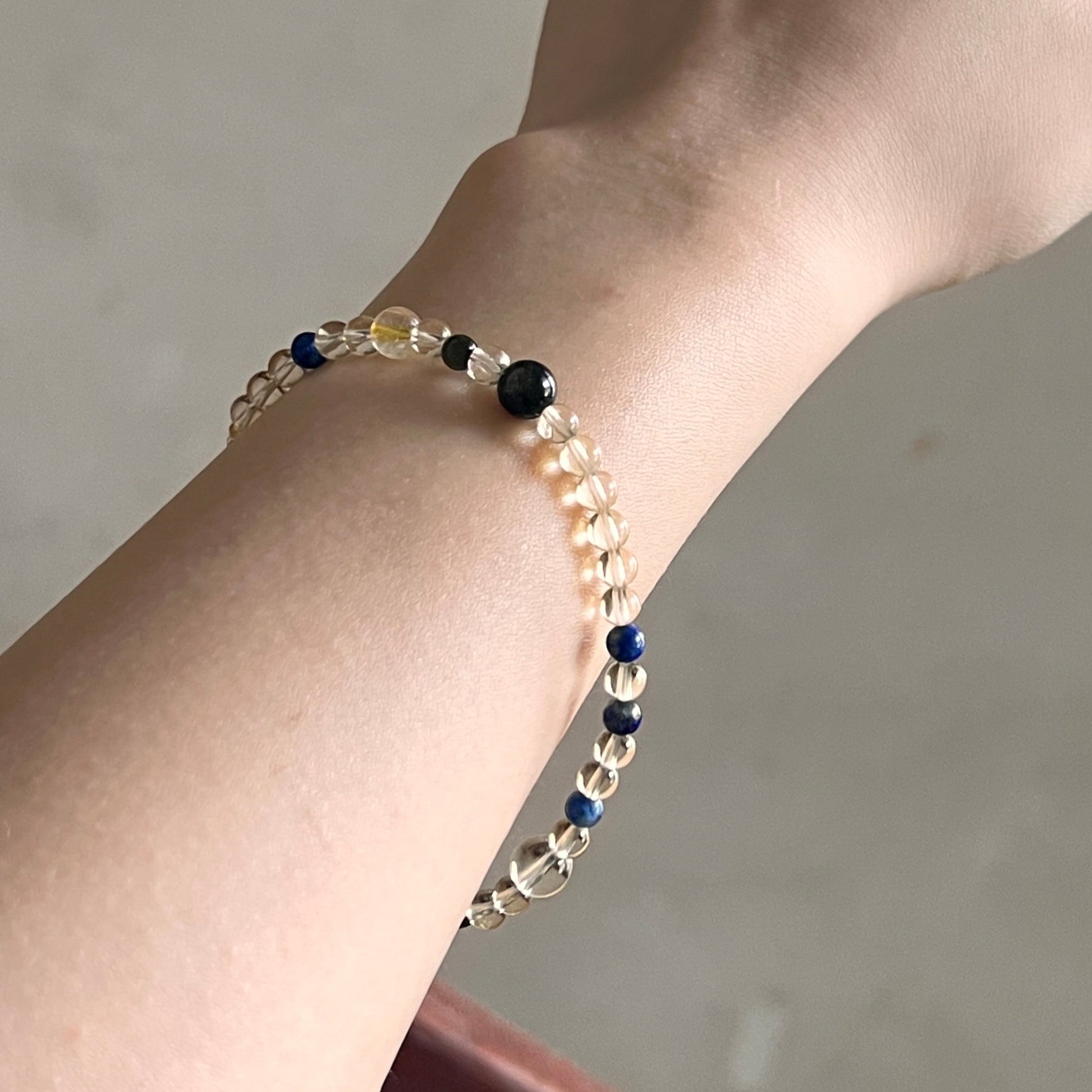 Hand wearing a beaded bracelet on a neutral background