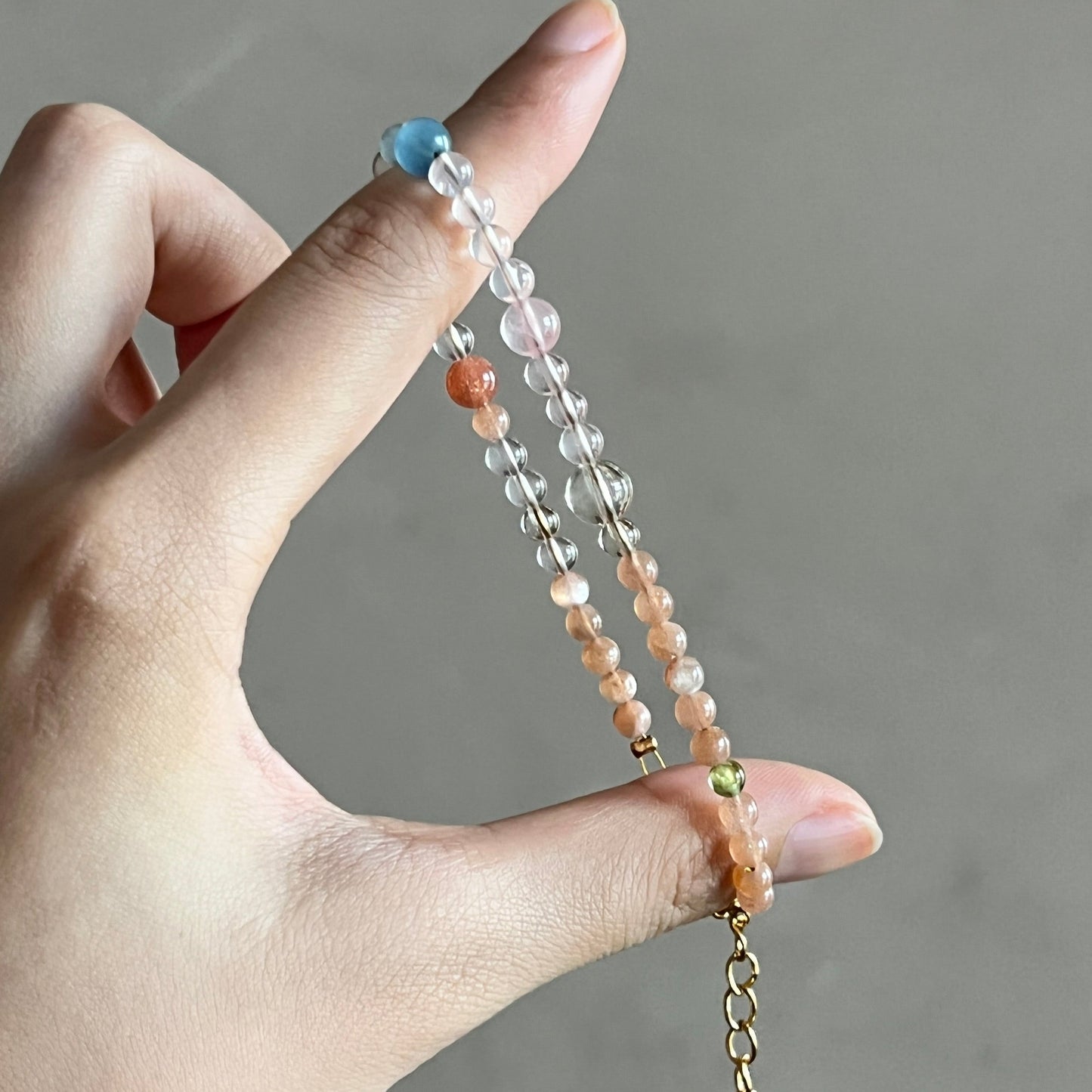 Hand holding a beaded bracelet against a neutral background