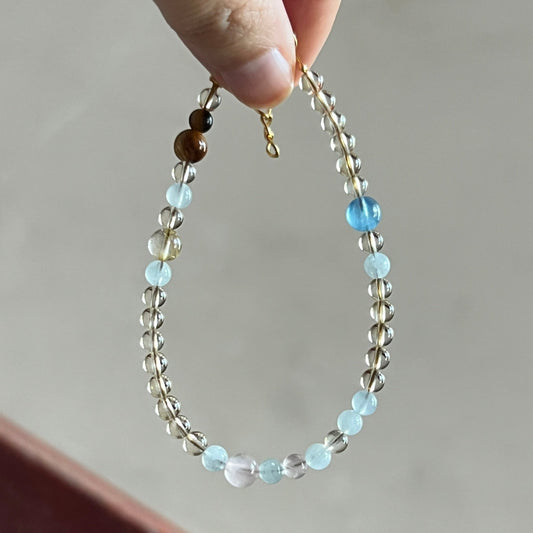 Hand holding a beaded bracelet with a neutral background