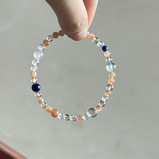 Hand holding a beaded bracelet on a neutral background