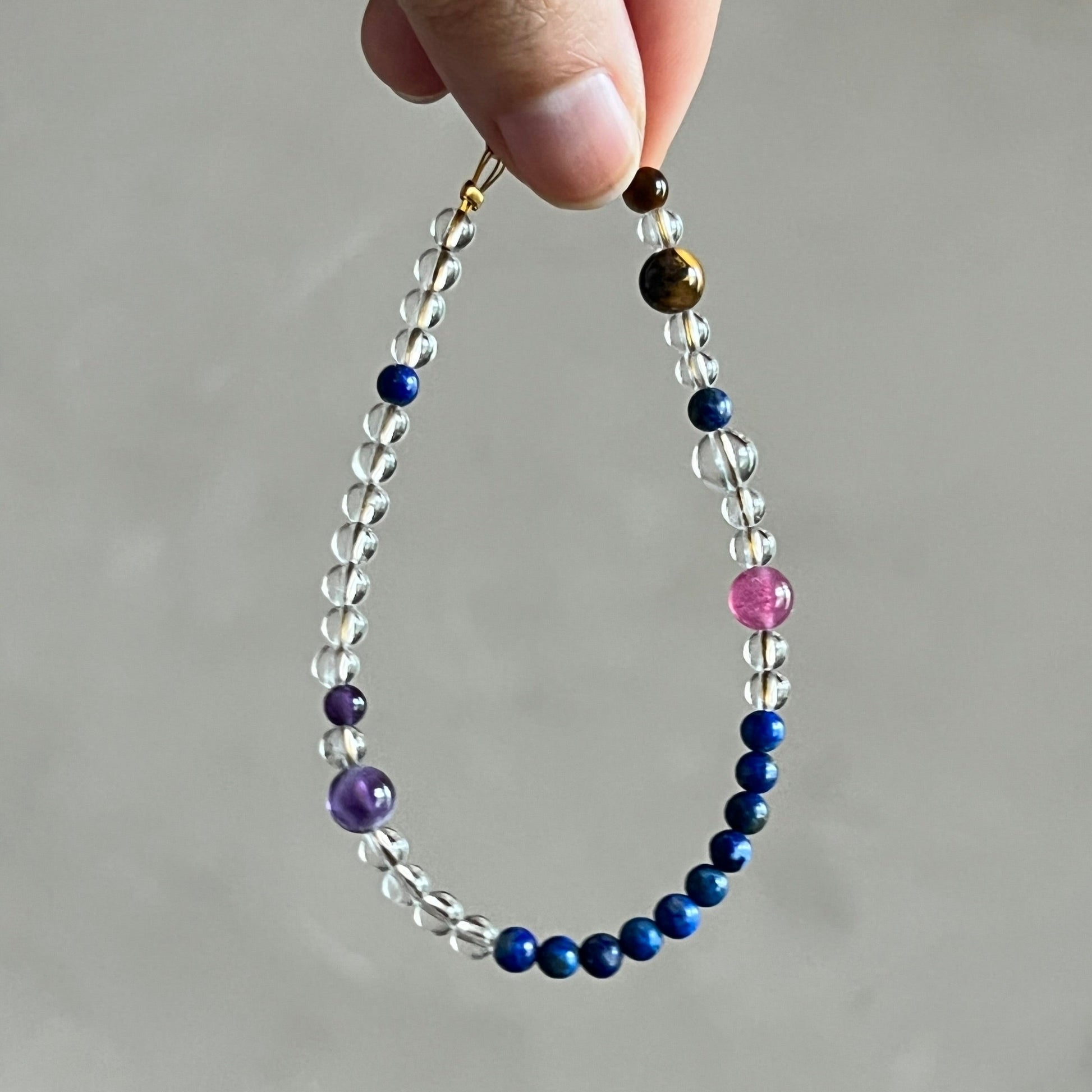 Beaded bracelet with multicolored beads held by a hand against a neutral background