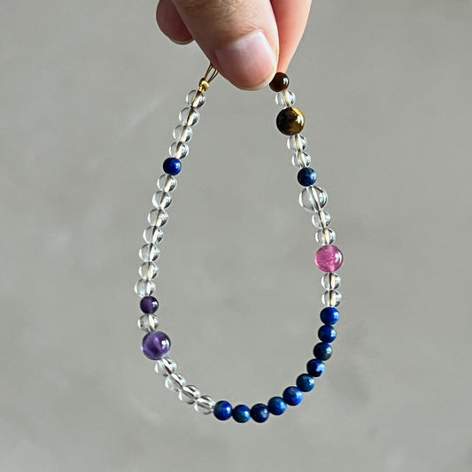 Beaded bracelet with multicolored beads held by a hand against a neutral background