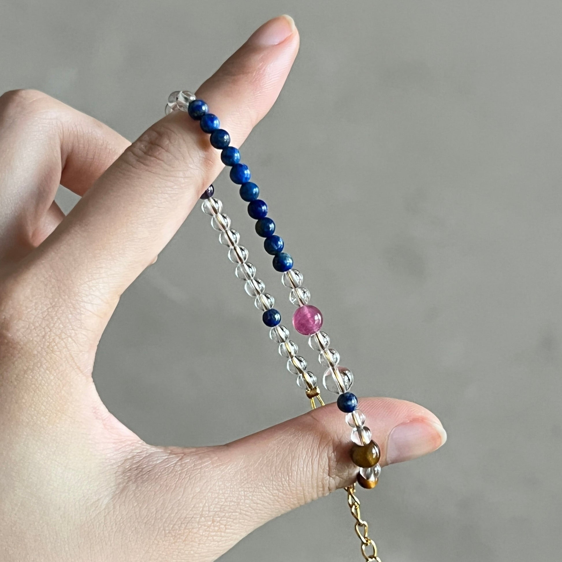 Hand holding a beaded necklace with a neutral background